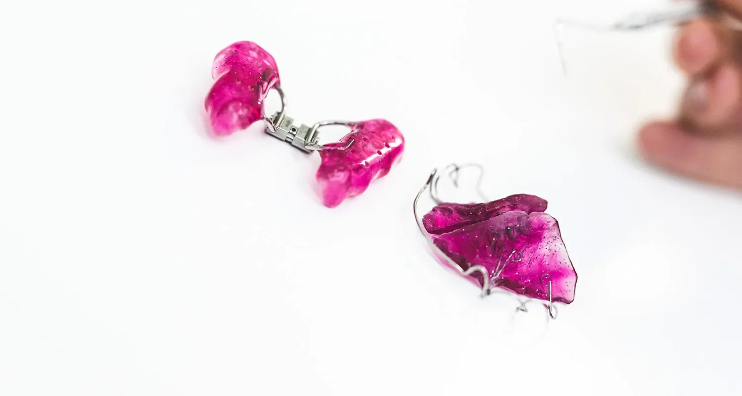 Rosa herausnehmbare Zahnspange mit Metallelementen.